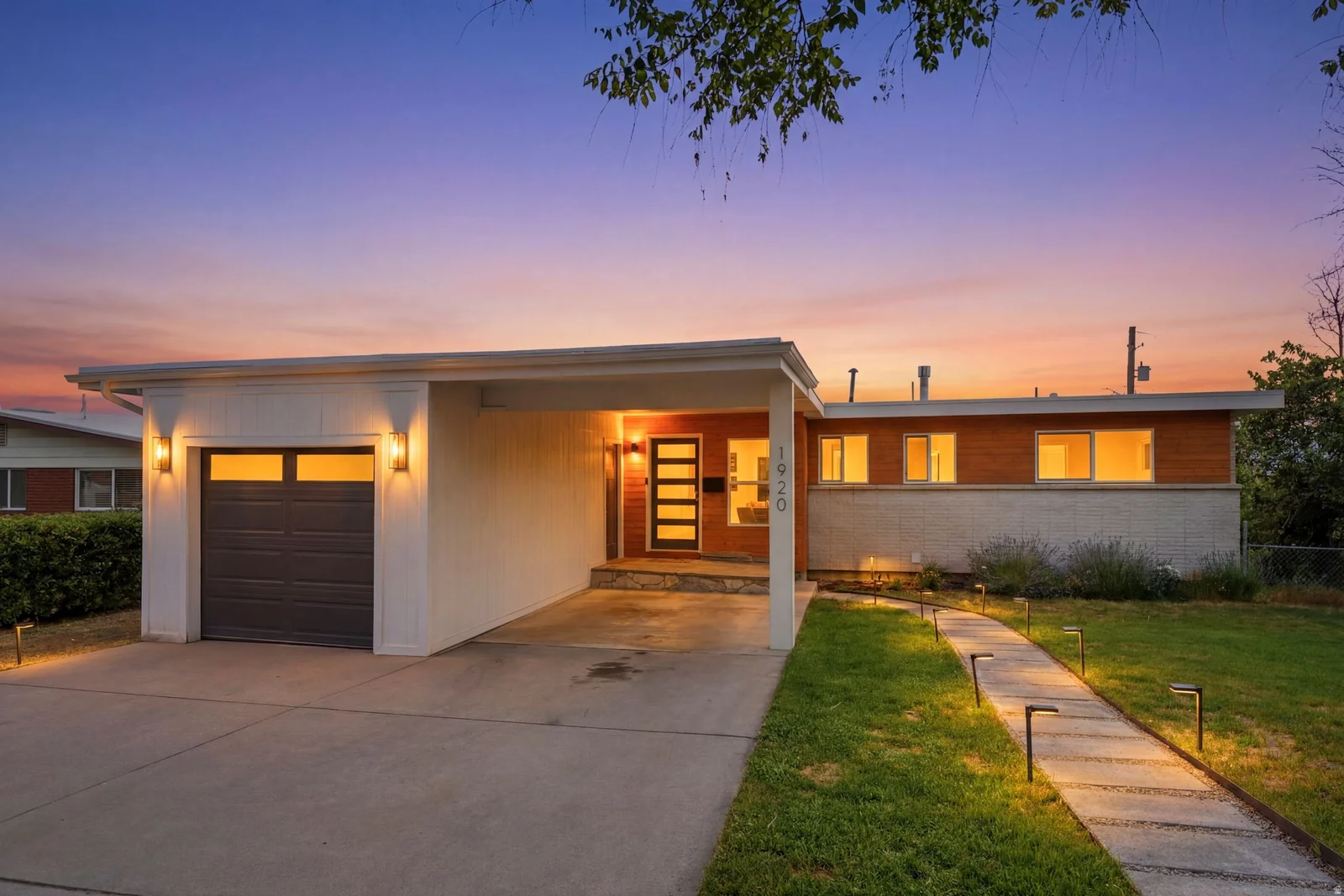 Contemporary residence featuring a wood-panel accent facade, white siding, and a dark garage door with windows